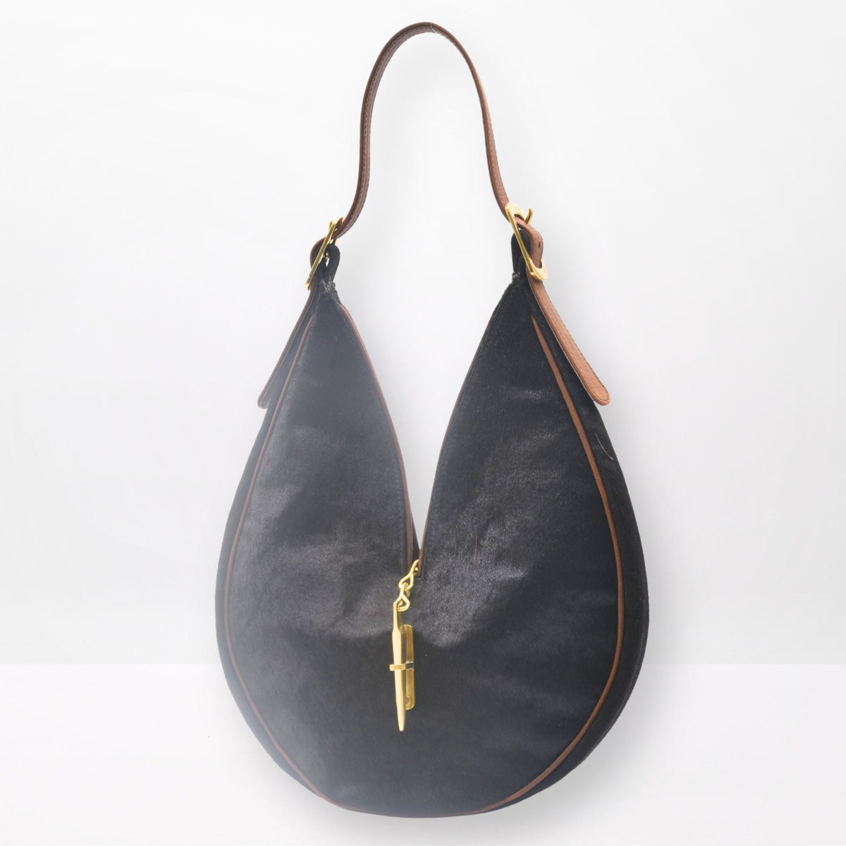 Round sculptural shoulder bag in dark brown cowhide with gold-brass hardware and signature closing system, handmade by Patricia Bos Designs.